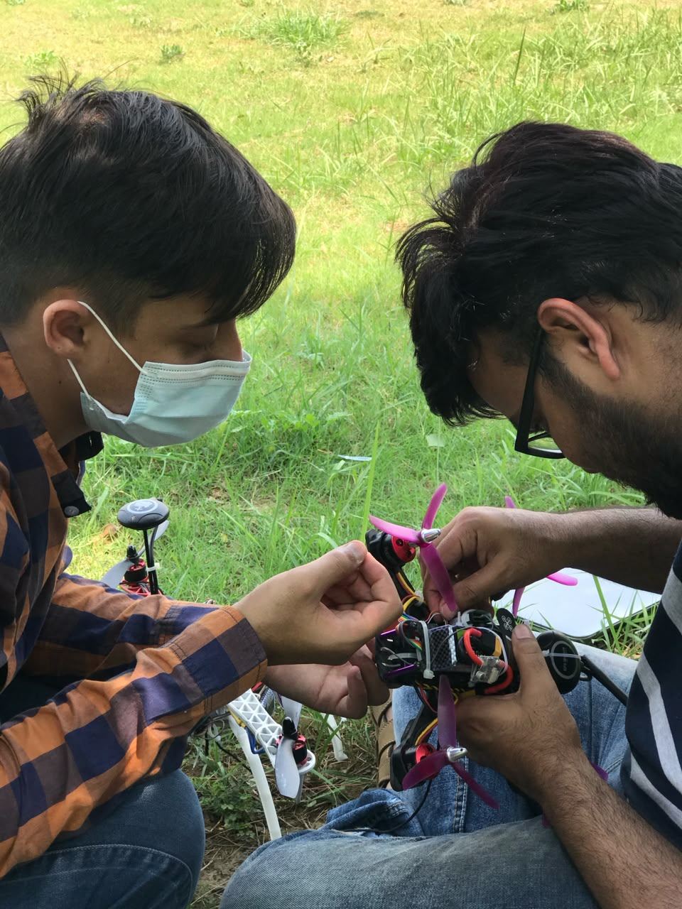 Two engineers assembling a multirotor airframe in a field before a test flight.