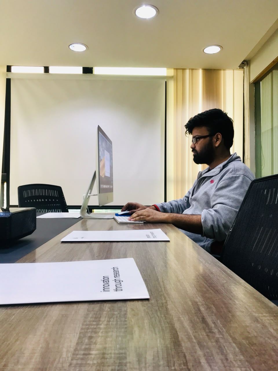 Working at a desk in front of a large monitor.